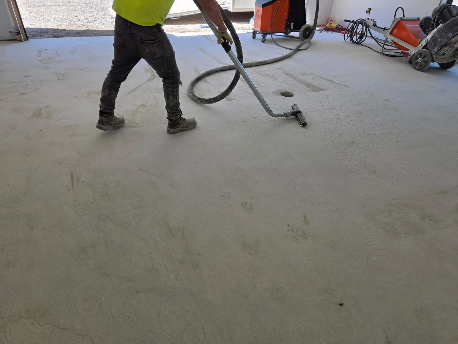 Operator grinding a concrete floor with vacuum dust collection
