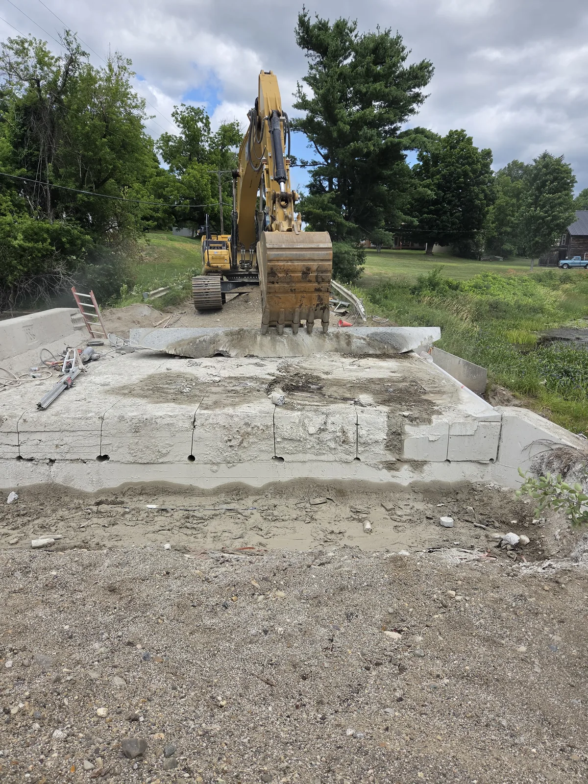 Excavator lifting a wire-sawn section of a bridge abutment