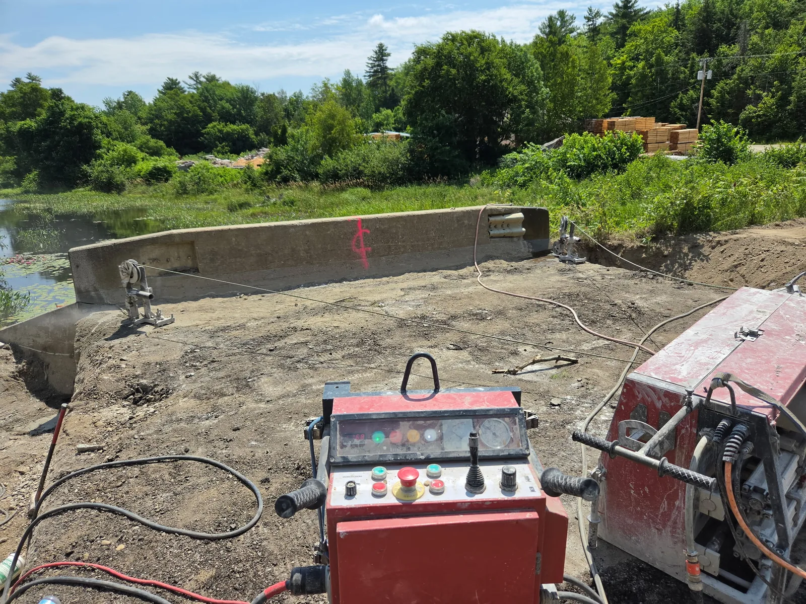 Wire saw control station set up beside a concrete structure at a waterside site